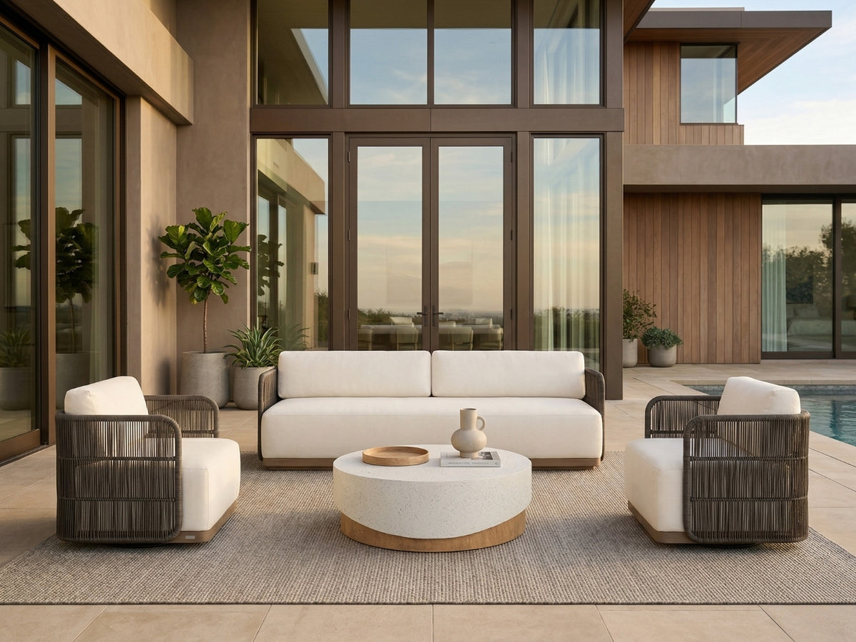 OROA classic contemporary patio with ivory seating, woven armchairs, a round stone coffee table, and poolside views beside a modern home.