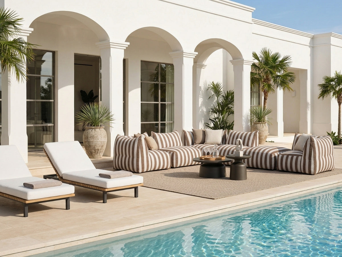 OROA Miami Art Deco poolside terrace with striped modular seating, sculpted arches, palm accents, and sleek loungers beside a villa.